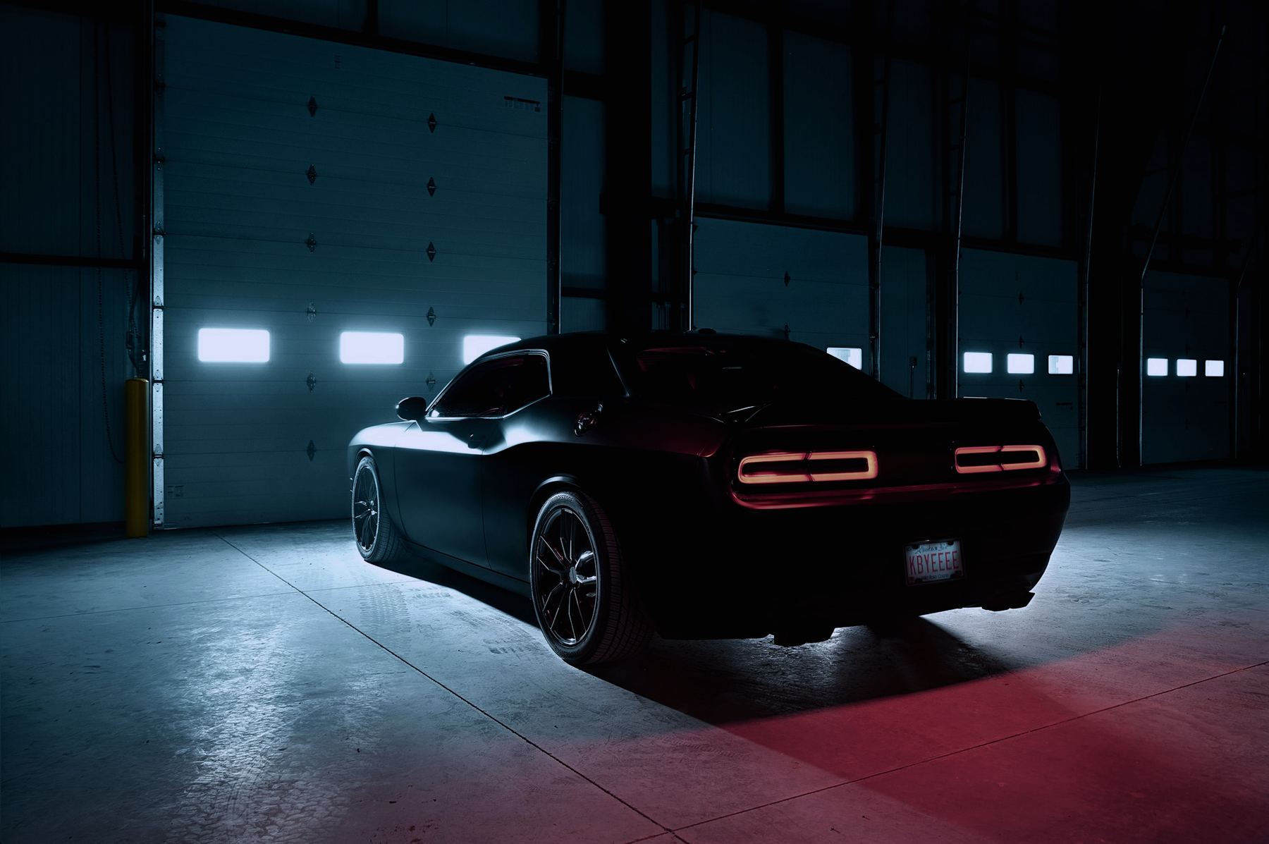 Dark muscle car parked in a lit workshop, windows tinted