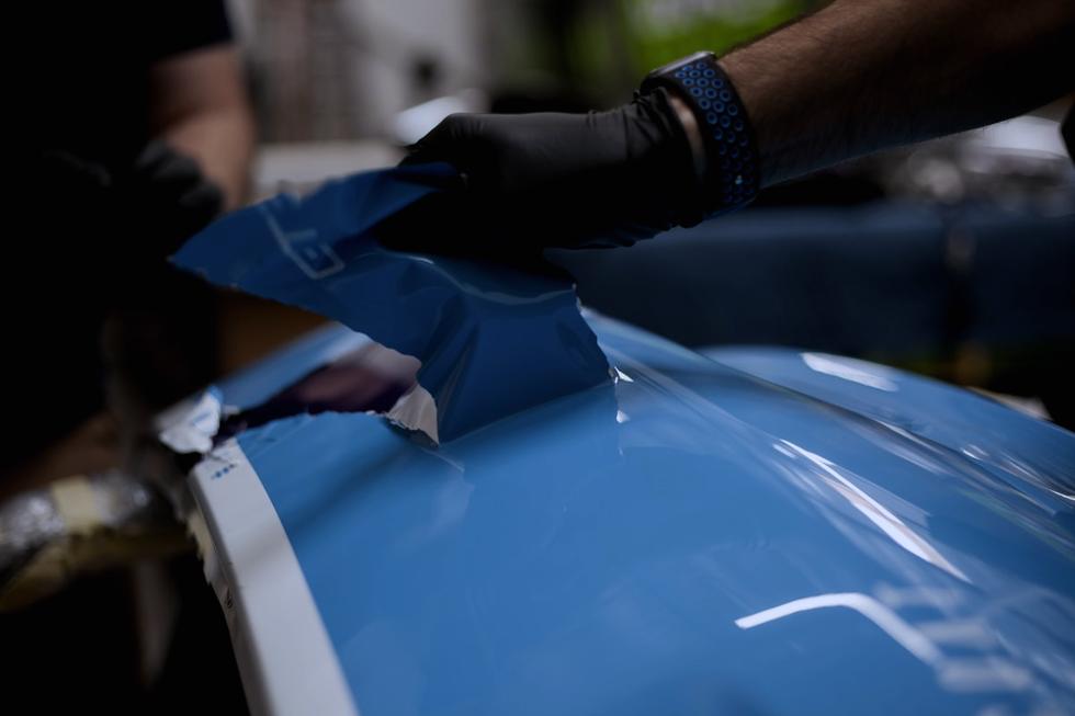 Installer laying vinyl film over a car panel