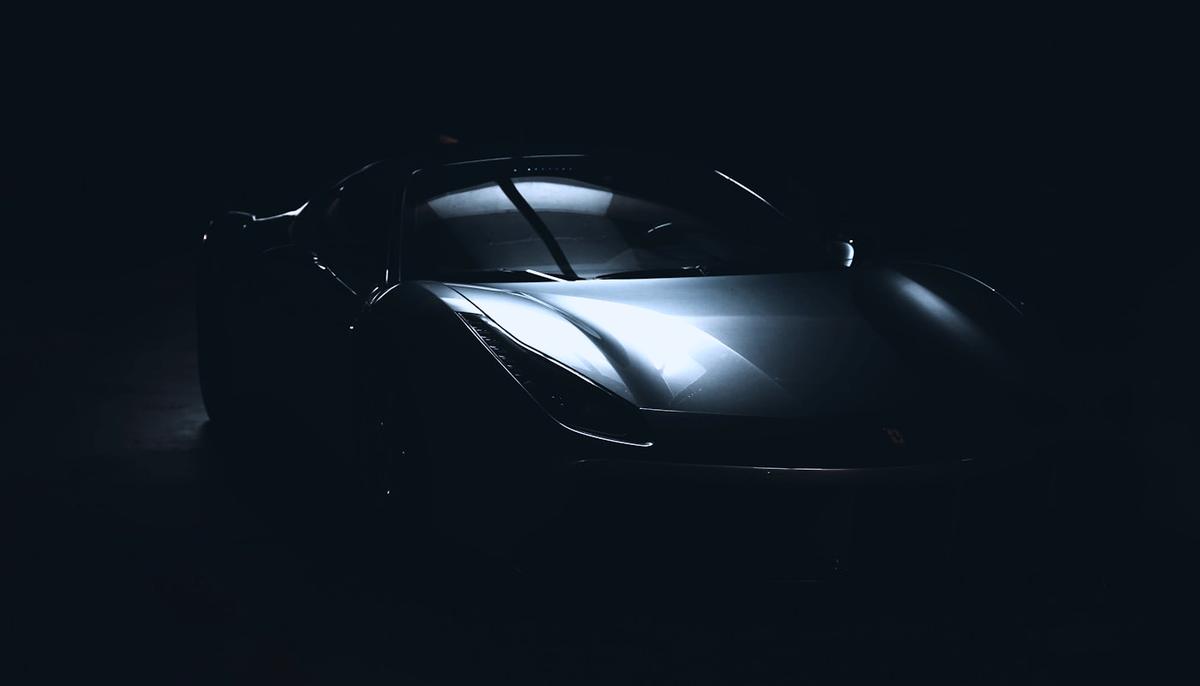 Dark sports car lit from one side in a studio