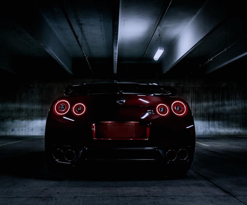 Rear of a dark sports car with glowing tail lights