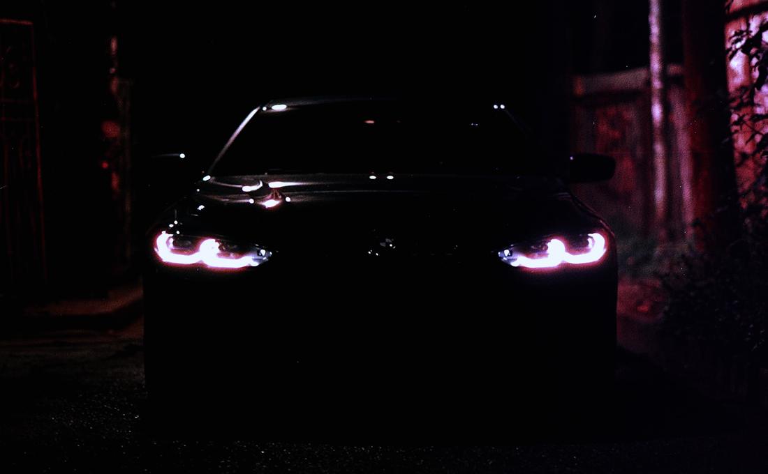 Dark sedan lit by red neon at night