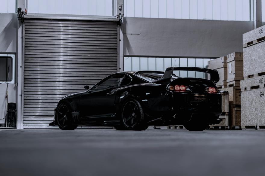 Black sports car parked outside an industrial unit